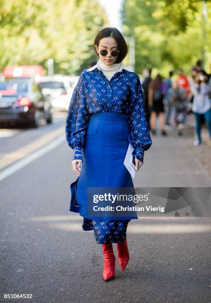 Yoyo Cao wearing blue skirt over blue dress, red boots is seen outside Fendi during Milan Fashion Week Spring/Summer 2018 on September 21, 2017 in...