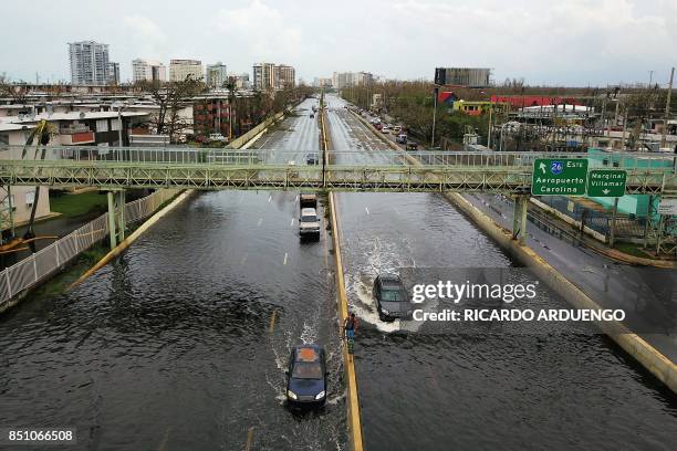 Cars drive through a flooded road in the aftermath of Hurricane Maria in San Juan, Puerto Rico, on September 21, 2017. Puerto Rico braced for...