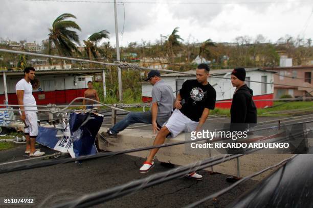 People pass over a downed power line concrete post in the aftermath of Hurricane Maria in Luquillo, Puerto Rico, Thursday, September 21, 2017. Puerto...