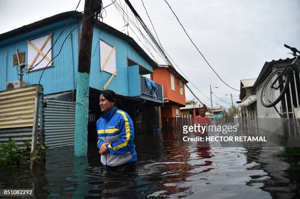 People walk accros a flooded street in Juana Matos, Puerto Rico, on September 21, 2017 as the country faced dangerous flooding and an island-wide...