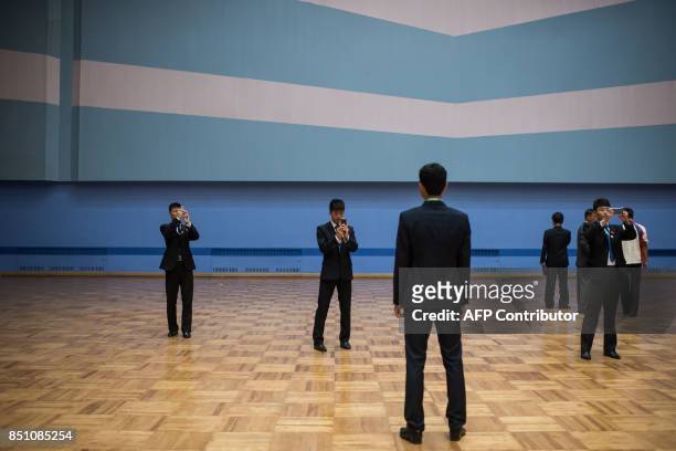 In a photo taken on September 21, 2017 North Korean staff members take photos during the 20th ITF World Taekwondo Championships in Pyongyang. The...