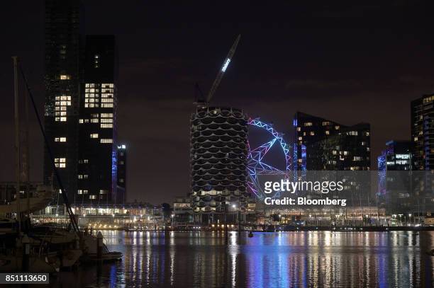 The Melbourne Star observation wheel is seen between residential buildings at night in the Docklands area of Melbourne, Australia on Thursday, July...