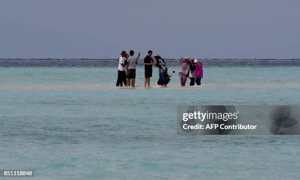 This photo taken on August 19, 2017 shows tourists standing on a sandbar in Raja Ampat -- which means Four Kings in Indonesian, in Indonesia's far...