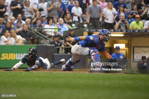 Keon Broxton of the Milwaukee Brewers beats a tag at home plate by Willson Contreras of the Chicago Cubs during the seventh inning of a game at...