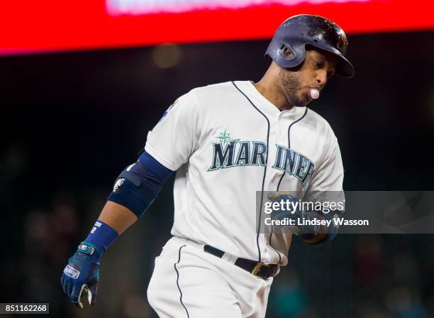 Robinson Cano of the Seattle Mariners blows a bubble as he rounds third base after hitting his 300th career home run off of Keone Kela of the Texas...