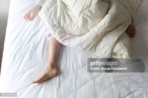 bare feet of a young woman on white bed - womans bare feet fotografías e imágenes de stock