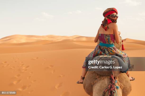 girl wearing turban rides camel on sahara desert - north africa landscape stock pictures, royalty-free photos & images