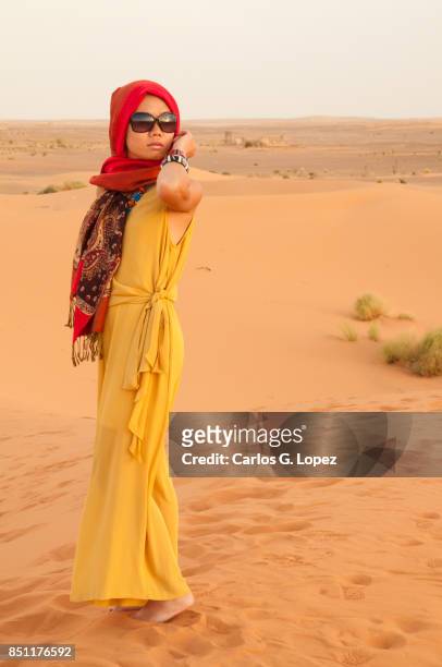 asian girl with head scarf standing on the sahara desert looking away - hot arabic girl stock pictures, royalty-free photos & images
