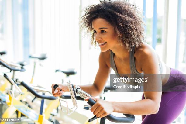 kvinnan gör konditionsträning på en stillastående cykel på gymmet - peloton bildbanksfoton och bilder