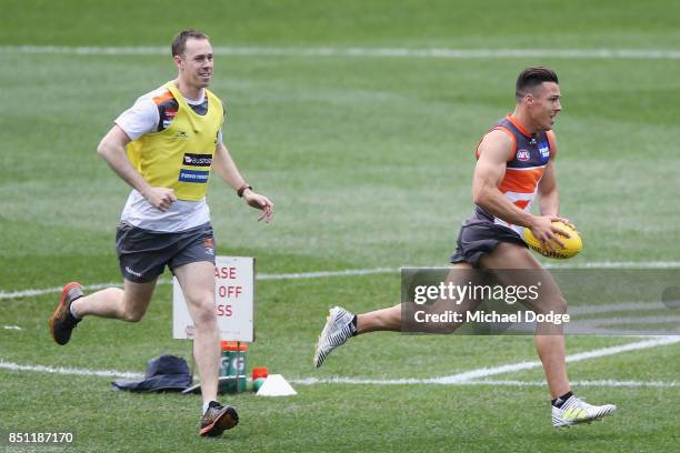 Dylan Shiel of the Giants runs with the ball next to assistant coach Nick Maxwell during the Greater Western Sydney Giants AFL training session at...