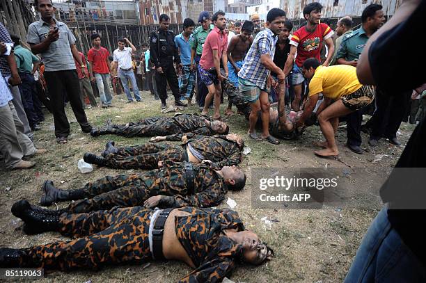 Bangladeshis carry the body of an Bangladesh Rifles officer from the Buriganga river as four other bodies lie on the ground in Dhaka on February 26...