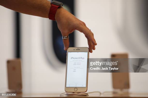 An Apple employee poses with the iPhone 8 on display at Apple Regent Street during the launch of the new phone on September 22, 2017 in London,...