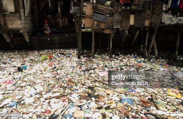 Woman takes a bath beside a garbage filled creek in Manila on September 22, 2017. - Giant Western consumer products brands led by Nestle, Unilever...