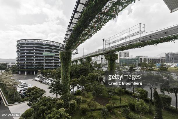 Elevated tracks for the BYD Co. SkyRail monorail system stand in front of a charging parking lot tower, left, at the company's headquarters in...