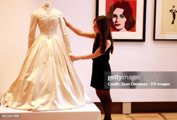 Christie's staff member adjusts a wedding dress worn by Elizabeth Taylor, for her first wedding to Conrad Nicky Hilton in 1950 which has an estimated...