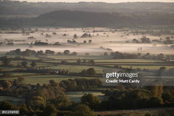 Early morning mist lingers in fields as the autumn sun rises over the Somerset Levels as viewed from Glastonbury Tor near Glastonbury on September...