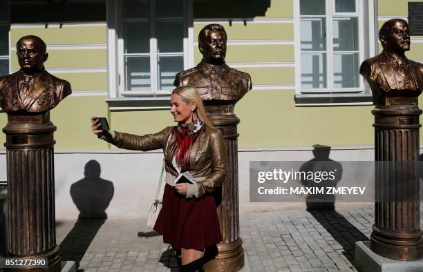 Woman takes a selfie picture in front of busts of Soviet Leaders Nikita Khrushchev, Joseph Stalin and Vladimir Lenin during a ceremony unveiling a...