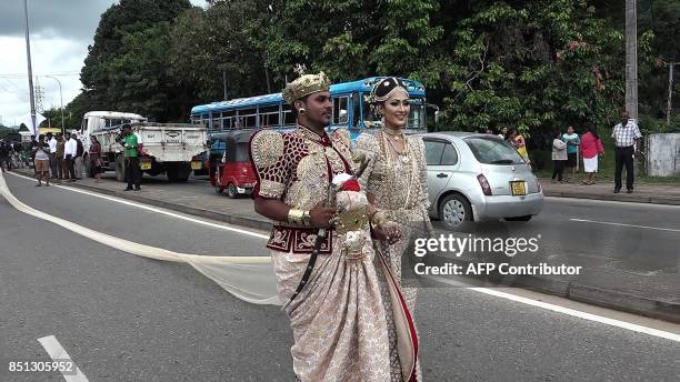 Sri Lankan wedding couple walk along a road as as a bride attempts to set a record for the longest wedding saree, with a lenght of 3.2 kms , in the...