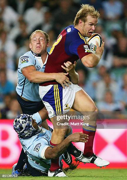 Jason Shoemark of the Highlanders is tackled by Brett Sheehan and Kurtley Beale of the Waratahs during the round three Super 14 match between the...
