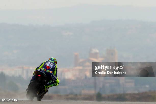 Valentino Rossi of Italy and Movistar Yamaha MotoGP rides backdropped by the Santa Maria la Mayor church in the nearby town of Alcaniz, during...