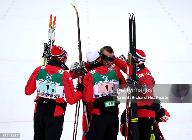 Eldar Roenning, Odd-Bjoern Hjelmeset, Tore Ruud Hofstad of Norway congratulate teammate Petter Northug as he crosses the line to win the gold medal...