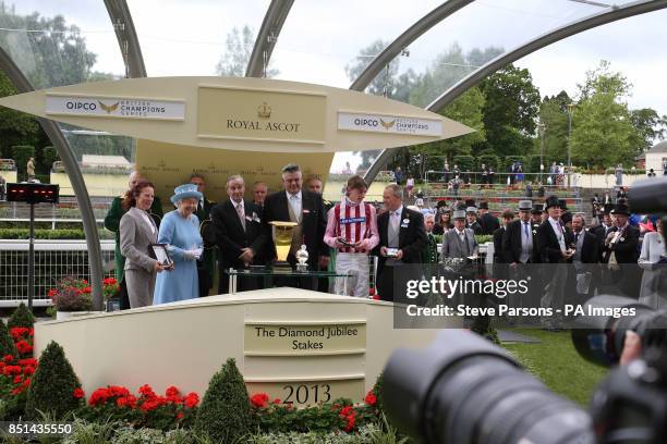 Queen Elizabeth II presents Diamond Jubilee Stakes trophy to jockey Adam Kirby after he won riding Lethal Force during day five of the Royal Ascot...