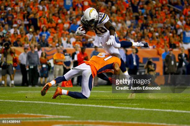 Running back Melvin Gordon of the Los Angeles Chargers dives over Strong safety Justin Simmons of the Denver Broncos for a touchdown at Sports...