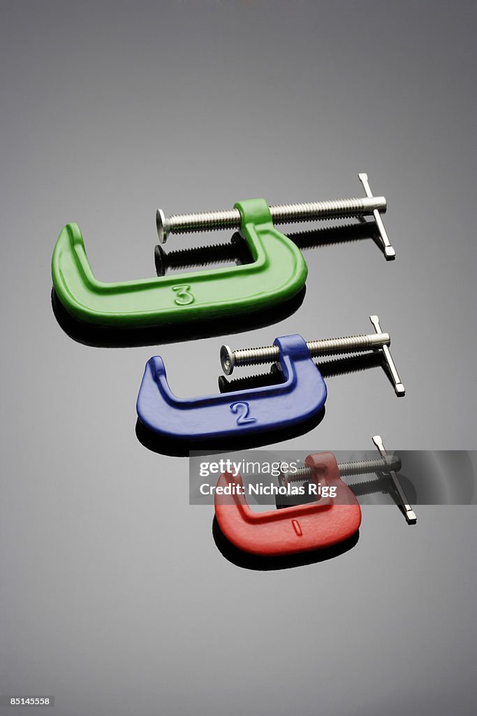 Three coloured g clamps on metallic background