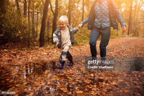 mother and child in the park - russia rain boots imagens e fotografias de stock