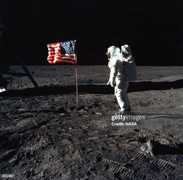 Astronaut Edwin E. Aldrin, Jr., the lunar module pilot of the first lunar landing mission, stands next to a United States flag July 20, 1969 during...