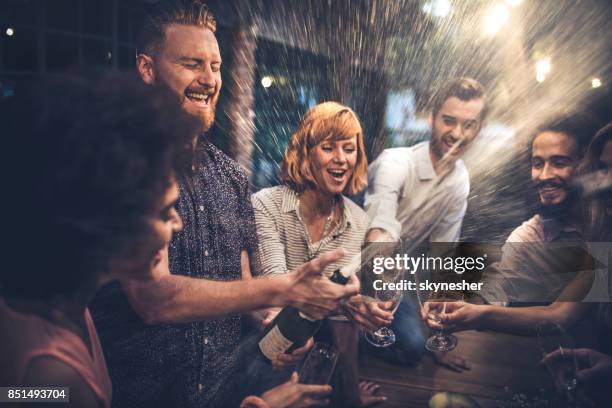 rothaarige menschen öffnen einen champagner auf einer party mit seinen freunden. - containment boom stock-fotos und bilder
