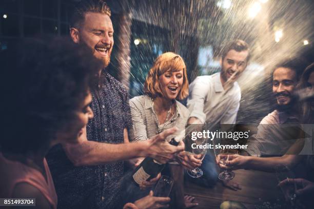 redhead man opening a champagne on a party with his friends. - champanhe imagens e fotografias de stock