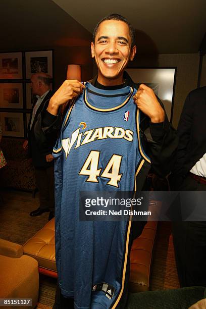 President Barack Obama poses with his Washington Wizards jersey during half time of the Washington Wizards game against the Chicago Bulls at the...