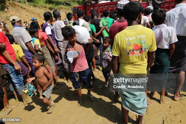 Rohingya Muslim child, fled from ongoing military operations in Myanmars Rakhine state, carries a bag of humanitarian aid as others stand in line at...