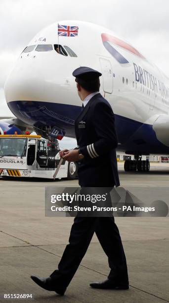 British Airways pilot walks in front of a British Airways Airbus A380, the world's largest passenger plane, at Heathrow Airport, as BA became the...