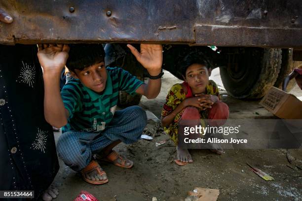 Kids shelter under a truck during an aid distribution on September 22, 2017 in Cox's Bazar, Bangladesh. Over 230,000 child refugees have fled into...