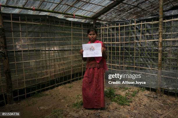 Year old Kurshida holds her drawing at a CODEC and UNICEF "child friendly space" on September 21, 2017 in Cox's Bazar, Bangladesh. Kurshida fled to...