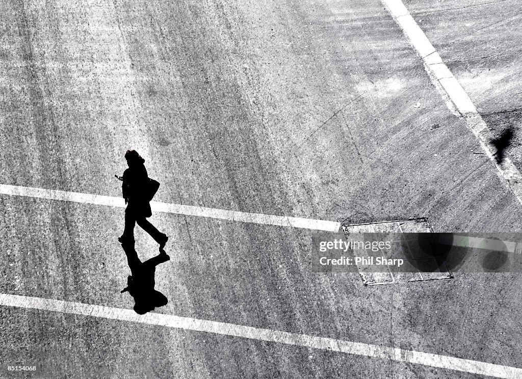 A women walking across a street using cell phone