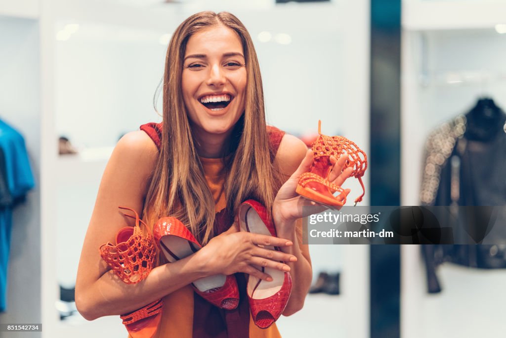 Attractive woman in the shoe store holding a pile of new shoes