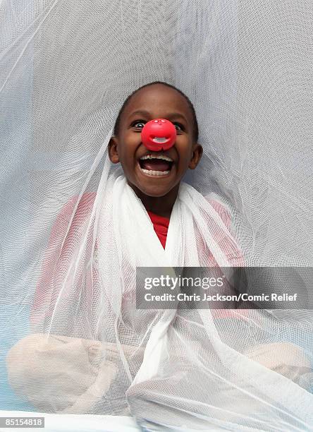 Child in a mosquito net poses for a photograph as GMTV presenter Ben Shephard learns about the work of the Comic Relief funded Mkombozi project for...