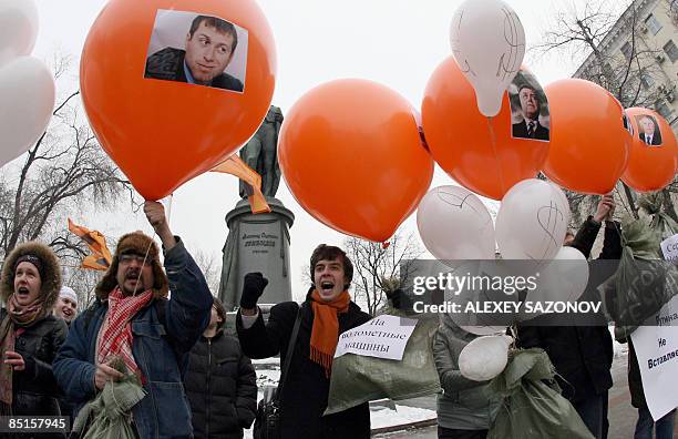 Russian opposition members hold baloons carrying posters of Russian tycoons in downtown Moscow on February 28 marking one year of the presidency of...