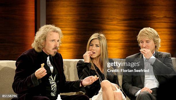 Host Thomas Gottschalk, actors Jennifer Aniston and Owen Wilson eat dog cakes as part of a challenge during the Wetten dass...? show at the Messe...