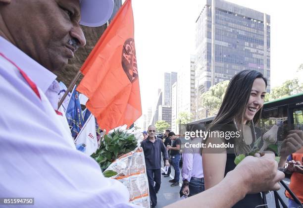 Man gives a flower away during a demonstration organised by the Central of Brazil's Workers and the other trade union centrals with demonstrators...