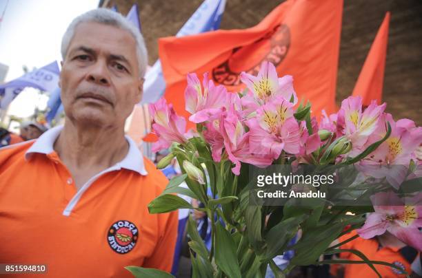 Man holds flowers during a demonstration organised by the Central of Brazil's Workers and the other trade union centrals with demonstrators carrying...