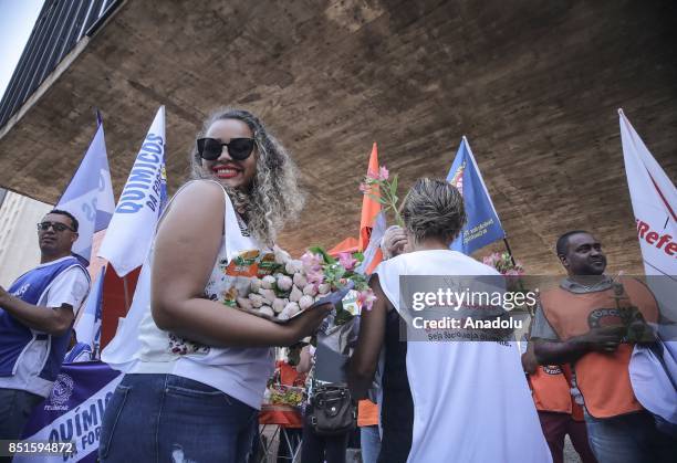 Woman gestures as she holds flowers during a demonstration organised by the Central of Brazil's Workers and the other trade union centrals with...