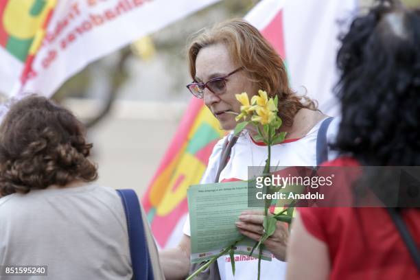 Woman holds flowers as she hands flyers out during a demonstration organised by the Central of Brazil's Workers and the other trade union centrals...