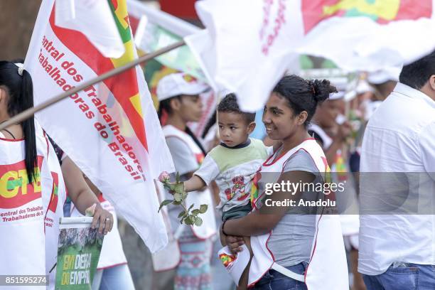 Woman holds a baby as the baby holds a flower during a demonstration organised by the Central of Brazil's Workers and the other trade union centrals...