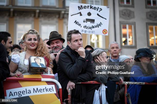 Iranian Woman in traditional bavarian dress with a purse showing Angela Merkel's portrait stands in front of protesters at Chancellor Angela Merkel's...