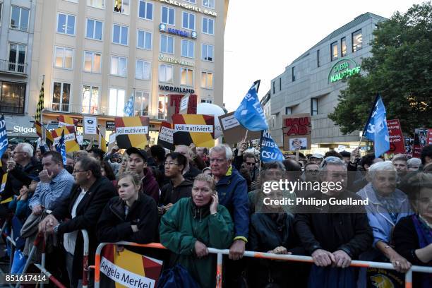 Supporters wave their signs as protesters hold a sign reading "Merkel has to go" at Chancellor Angela Merkel's last big election campaign rally...