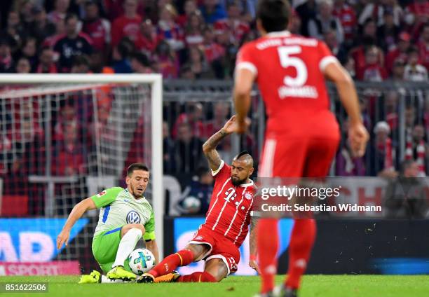 Arturo Vidal of Muenchen fouls Ignacio Camacho of Wolfsburg during the Bundesliga match between FC Bayern Muenchen and VfL Wolfsburg at Allianz Arena...